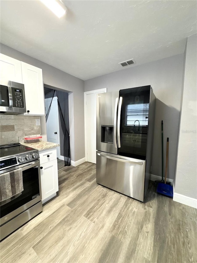 kitchen featuring stainless steel appliances, visible vents, white cabinetry, backsplash, and light wood finished floors