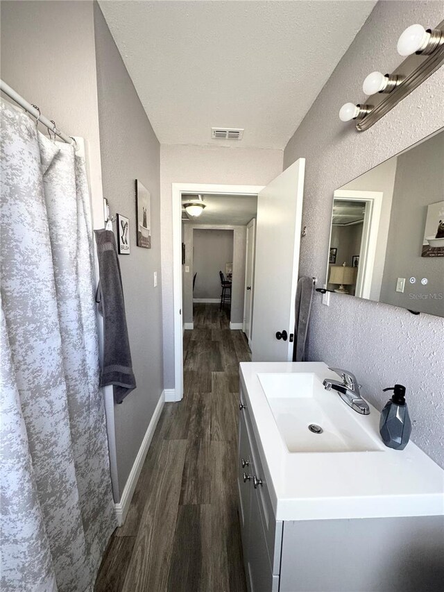 full bathroom with vanity, wood finished floors, visible vents, and baseboards