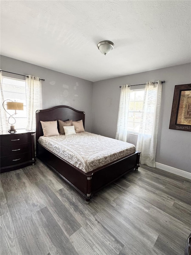 bedroom with a textured ceiling, wood finished floors, and baseboards