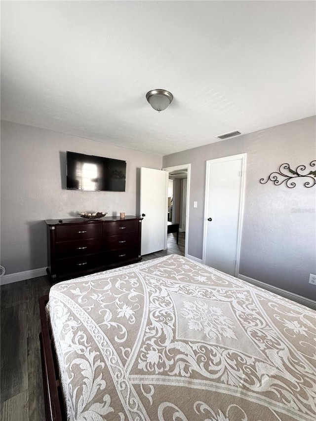 bedroom with visible vents, dark wood finished floors, and baseboards