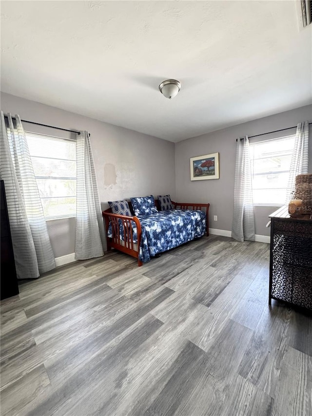 bedroom with visible vents, baseboards, and wood finished floors