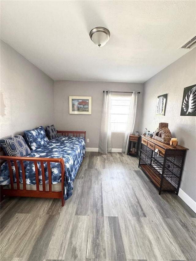 bedroom with a textured ceiling, wood finished floors, and baseboards