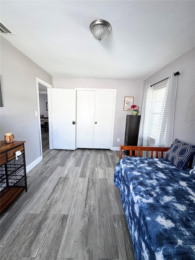 bedroom featuring visible vents, baseboards, and wood finished floors