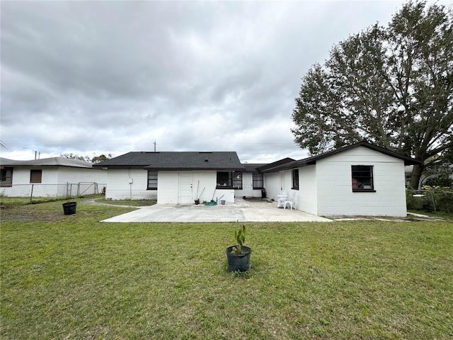 back of house featuring concrete block siding, a fenced backyard, a patio, and a lawn