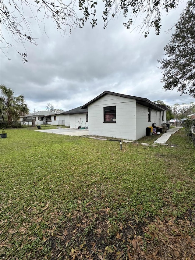 view of side of home featuring concrete driveway and a lawn