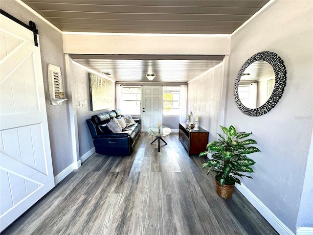 interior space featuring wooden ceiling, a barn door, baseboards, and wood finished floors
