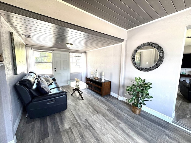 living area featuring wooden ceiling, crown molding, baseboards, and wood finished floors