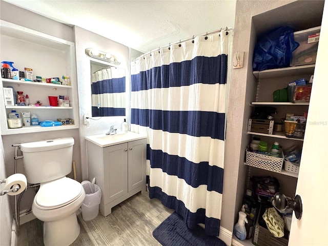 bathroom with toilet, a shower with curtain, wood finished floors, vanity, and a textured ceiling