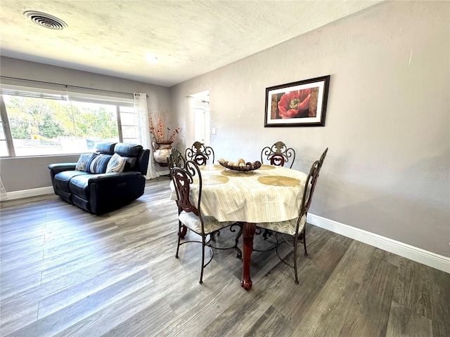 dining space with baseboards, visible vents, and wood finished floors