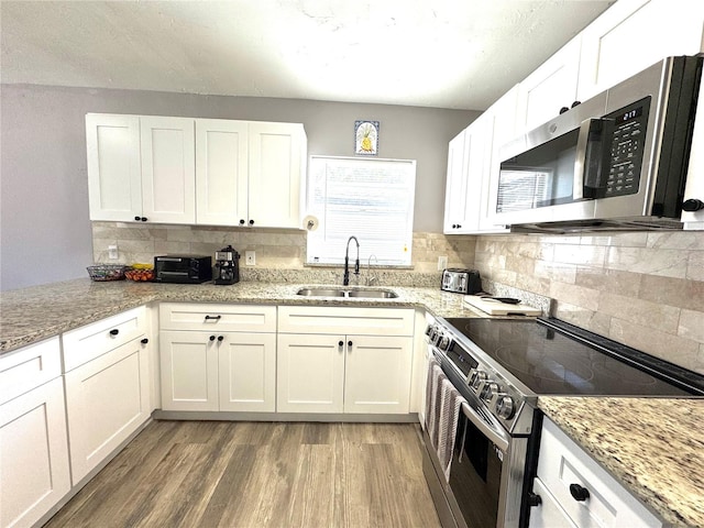 kitchen featuring a sink, white cabinetry, light wood-style floors, and appliances with stainless steel finishes