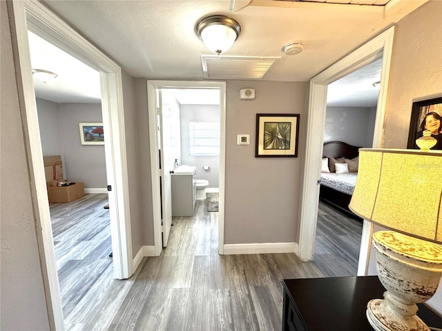 hall featuring baseboards, visible vents, and wood finished floors