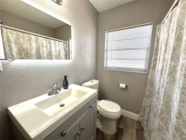 full bath featuring toilet, wood finished floors, a shower with curtain, baseboards, and vanity