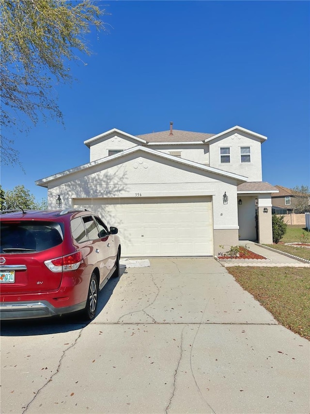 view of front of house with an attached garage, concrete driveway, and stucco siding