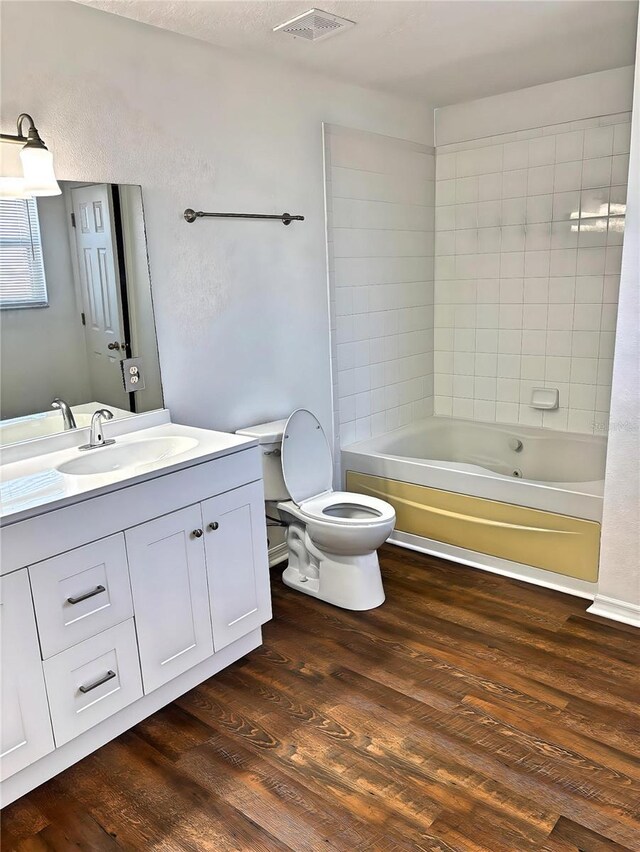 full bath featuring visible vents, toilet, wood finished floors, shower / bath combination, and vanity