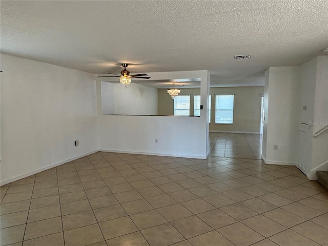 spare room with visible vents, ceiling fan with notable chandelier, a textured ceiling, stairway, and light tile patterned floors