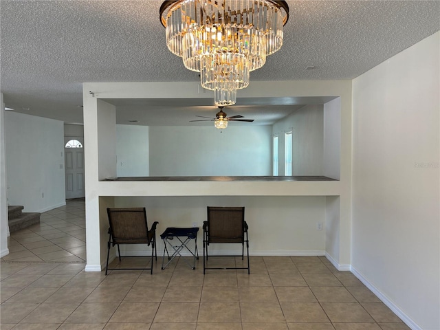 kitchen with a textured ceiling, tile patterned floors, baseboards, and ceiling fan