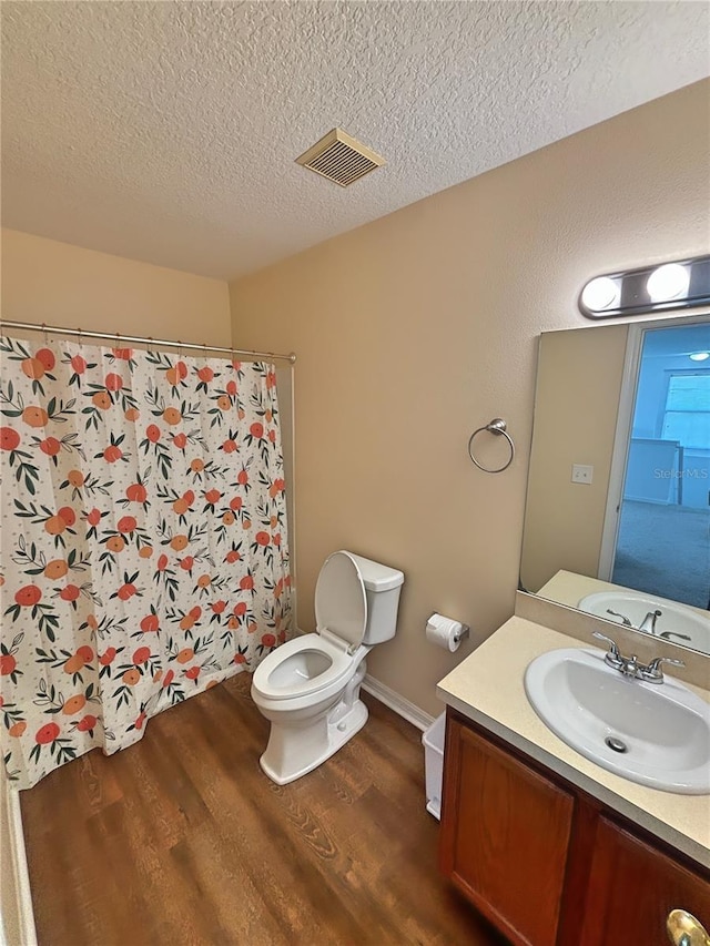 full bath with visible vents, toilet, vanity, wood finished floors, and a textured ceiling