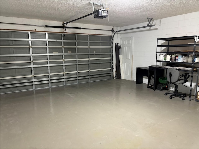 garage with a garage door opener and concrete block wall