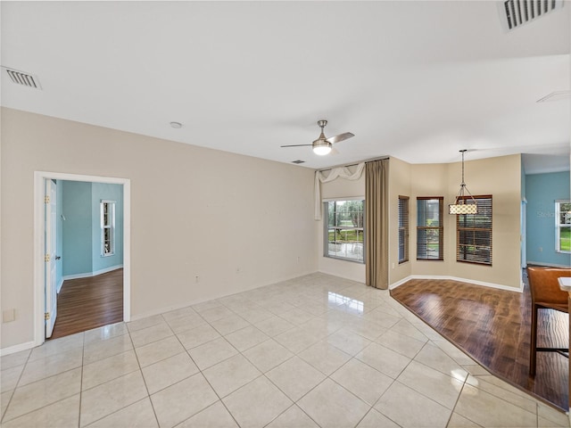 empty room with light tile patterned floors, baseboards, visible vents, and a ceiling fan