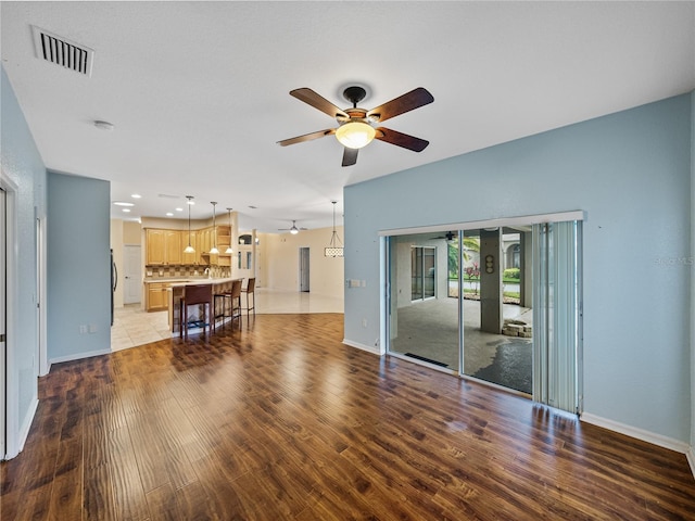 unfurnished living room featuring visible vents, ceiling fan, light wood-style flooring, and baseboards
