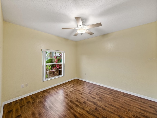 unfurnished room with dark wood-style floors, a textured ceiling, and baseboards