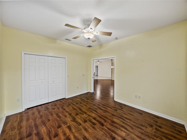 unfurnished bedroom featuring baseboards, visible vents, dark wood-style floors, ceiling fan, and a closet