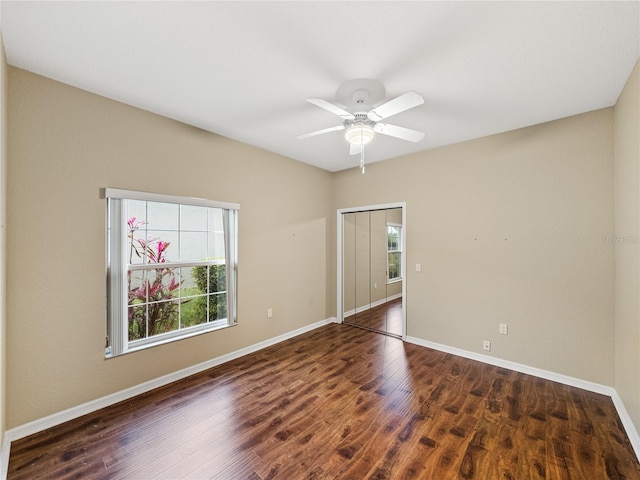 spare room featuring dark wood-style floors, ceiling fan, and baseboards
