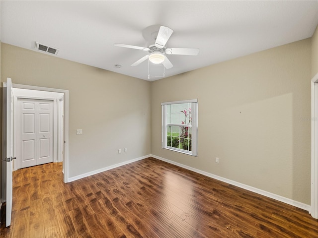 empty room with a ceiling fan, wood finished floors, visible vents, and baseboards
