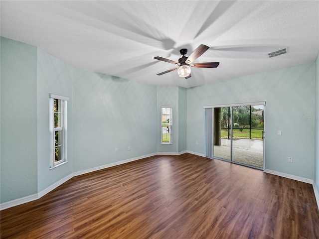 unfurnished room with baseboards, visible vents, dark wood finished floors, ceiling fan, and a textured ceiling