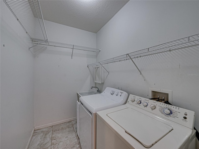 laundry area with a textured ceiling, laundry area, separate washer and dryer, a sink, and baseboards