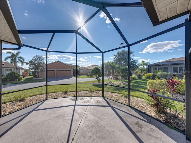view of patio / terrace featuring a lanai, a garage, a residential view, and an outbuilding