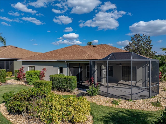 rear view of property with a patio, glass enclosure, a shingled roof, a ceiling fan, and stucco siding