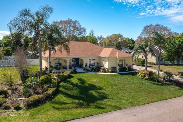 mediterranean / spanish house with a front yard, fence, and stucco siding