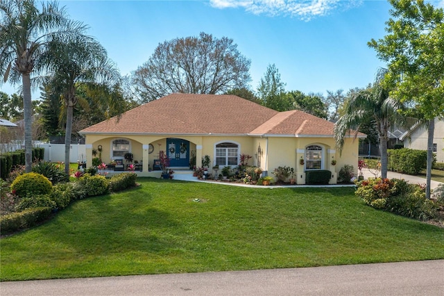 mediterranean / spanish-style home featuring stucco siding, a front yard, and fence