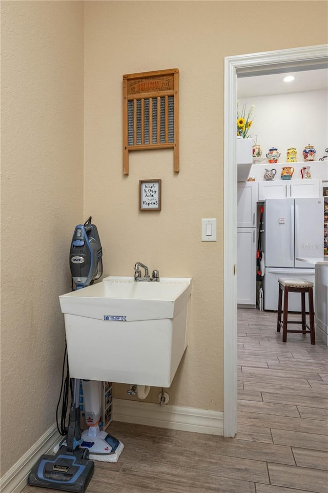 bathroom with wood finished floors, baseboards, and a sink