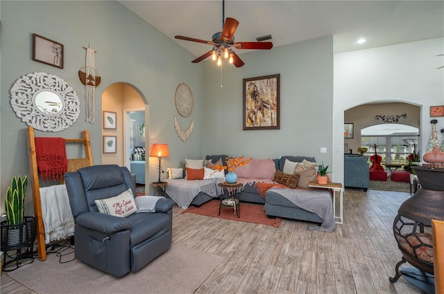 living area with arched walkways, visible vents, a towering ceiling, and wood finished floors