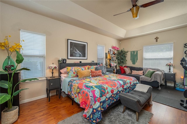 bedroom with a ceiling fan, wood finished floors, and baseboards