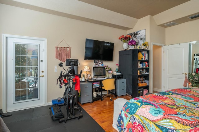 bedroom with visible vents, lofted ceiling, and wood finished floors