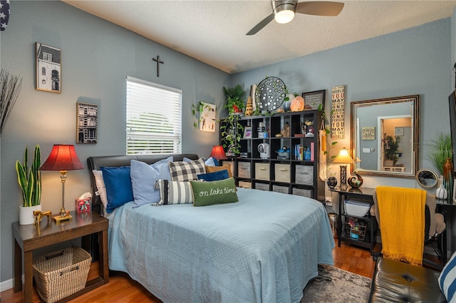 bedroom with a textured ceiling, a ceiling fan, and wood finished floors