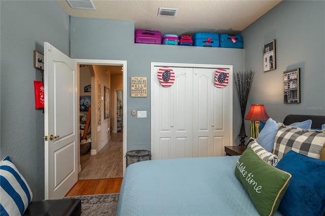 bedroom featuring a closet, visible vents, and wood finished floors