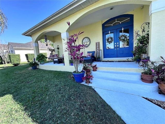 doorway to property with french doors, a lawn, and stucco siding