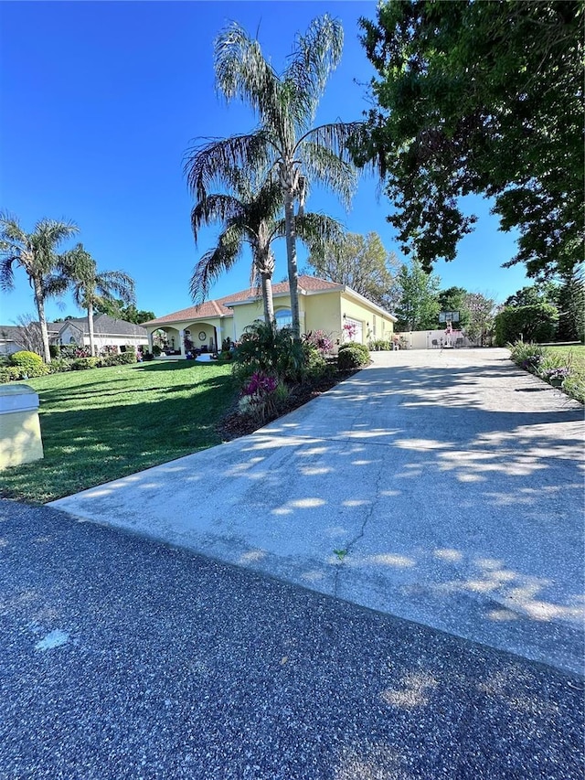 exterior space featuring concrete driveway, a yard, and a garage