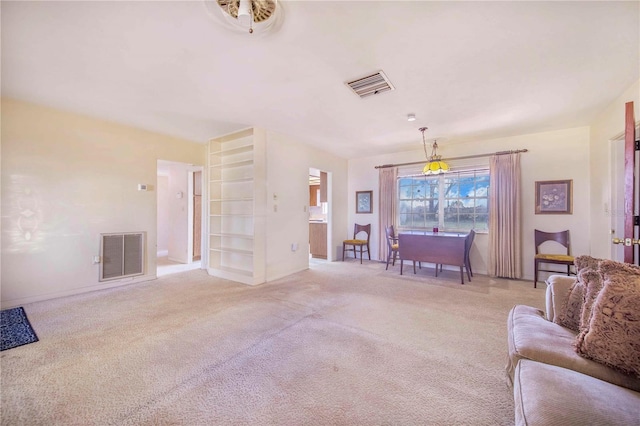 living area featuring baseboards, visible vents, and light colored carpet