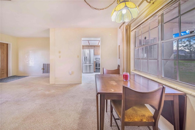 dining area featuring baseboards, visible vents, and light colored carpet