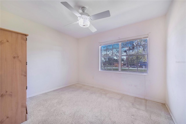 carpeted empty room featuring ceiling fan and baseboards