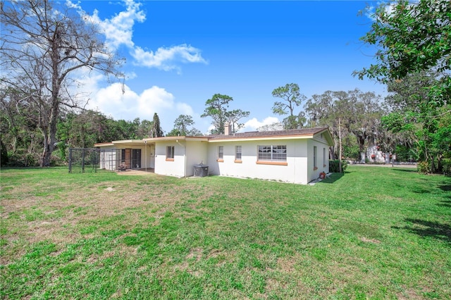 rear view of property featuring fence, a yard, a chimney, and stucco siding