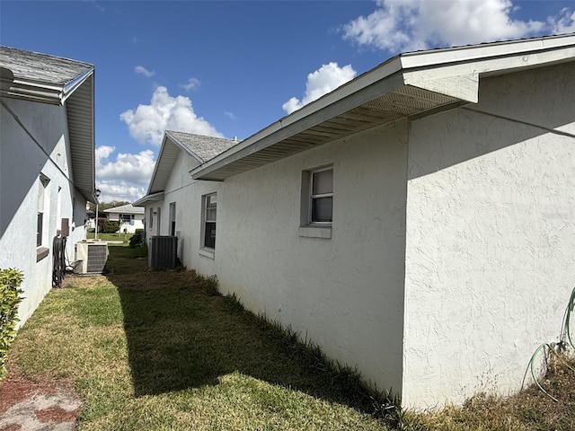 view of side of property with a yard, cooling unit, and stucco siding