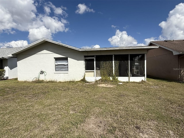 rear view of property with a sunroom, a lawn, and stucco siding