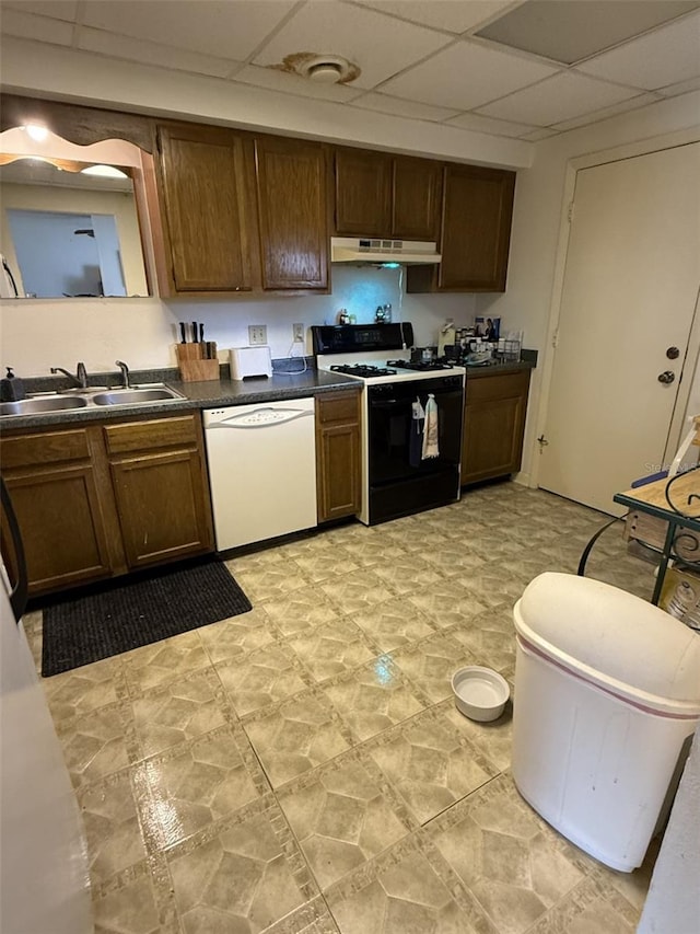 kitchen with range with gas stovetop, dishwasher, dark countertops, under cabinet range hood, and a sink