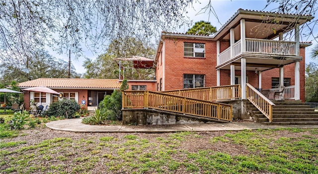 rear view of property featuring a balcony and brick siding